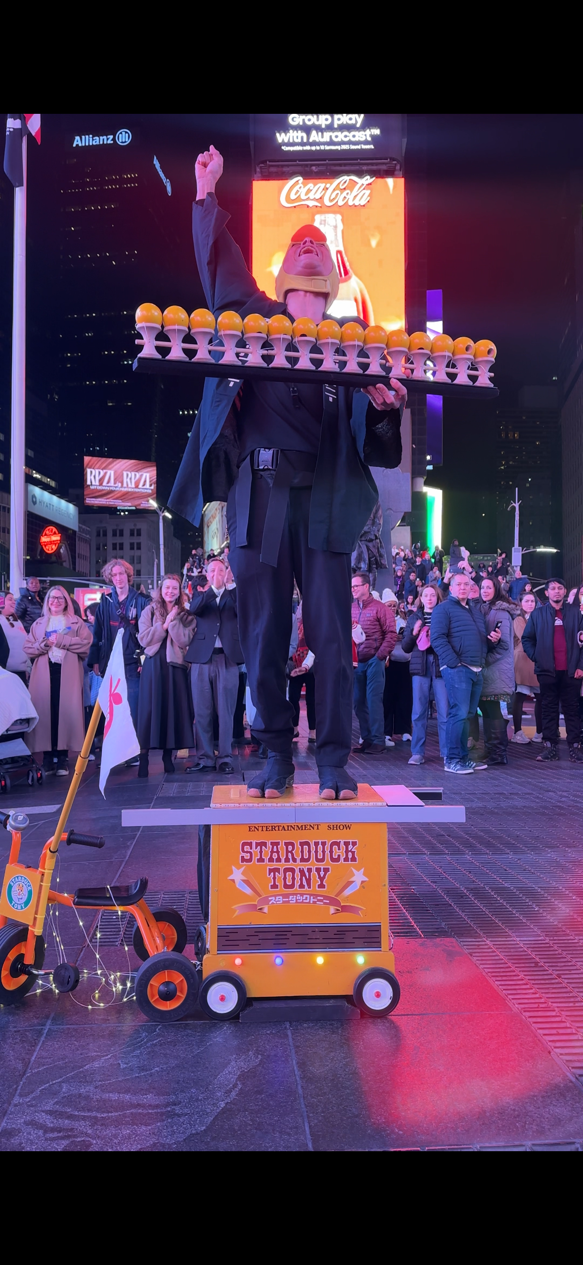 Starduck Tony holding kendama on his tricycle stage in Times Square, New York, in 2025